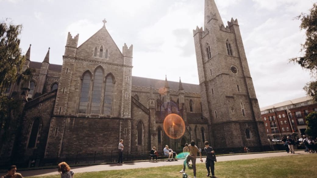 View of Saint Patrick's Cathedral with people enjoying a sunny day in Dublin, Ireland.