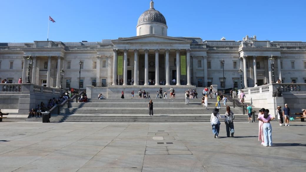 The National Gallery in Trafalgar Square, London, with people enjoying a sunny day.