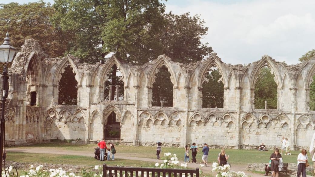 Visitors explore the medieval ruins of St. Mary's Abbey on a sunny day in York, England.