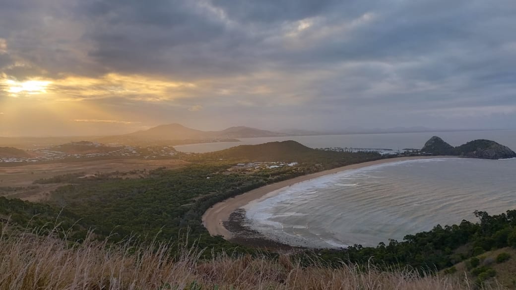 A beautiful sunset view of a bay on a moody sky day, as seen from the Bluff Point Walking Track in the Capricorn Coast National Park.