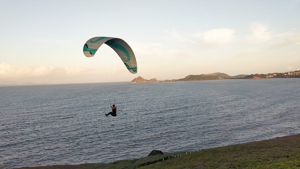 A paraglider soars beside Wreck Point lookout on the Capricorn Coast, with the ocean below.