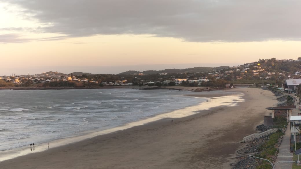 A sunset view on a moody sky day over Yeppoon's main beach from the Spring Head Lookout.