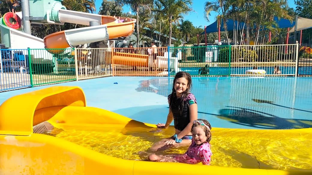 Ayla and Romy sit at the bottom of a slide at Coolwaters Yeppoon, a fantastic place for families to stay or visit for the day.
