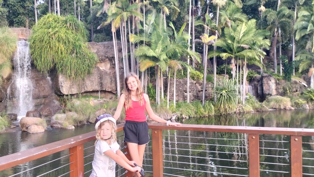 Ayla and Romy stand on a viewing platform in front of a small waterfall at Kershaw Gardens in Rockhampton.