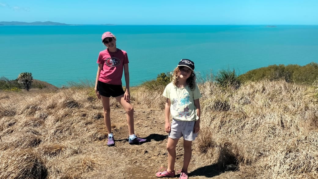 Ayla and Romy stop for a photo at the top of the Bluff Point Walking Track on the Capricorn Coast, with the turquoise ocean behind.