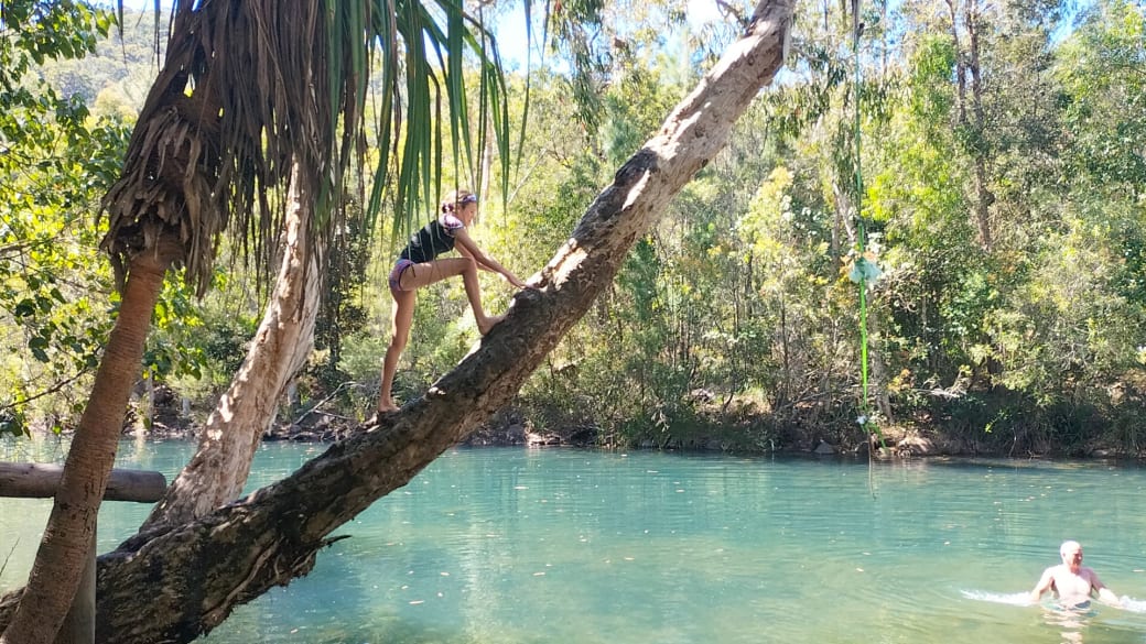 Ayla climbs a tree above the water, with Colin in the water below at Upper Stoney Creek in Byfield, not far from Yeppoon.