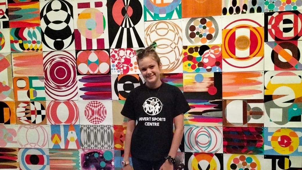 Ayla stands in front of a colourful piece of artwork at the Rockhampton Museum of Art.