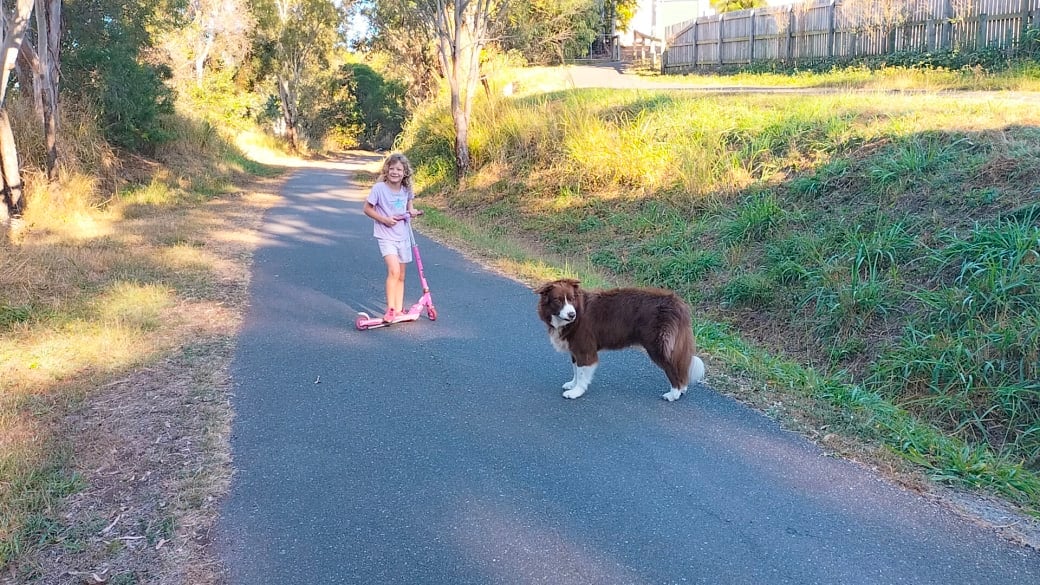 Romy rides her scooter along the Pineapple Trail in Yeppoon, while Millie the dog follows behind.