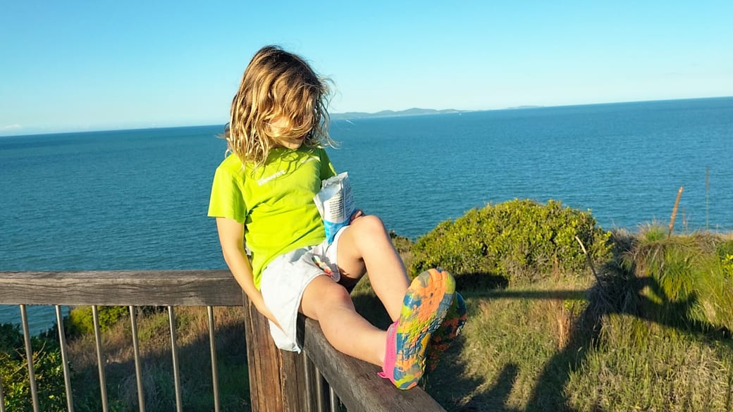Romy sits on a fence and enjoys the views across the bright blue sea from the Fan Rock Lookout in the Double Heads section of the Capricorn Coast National Park.