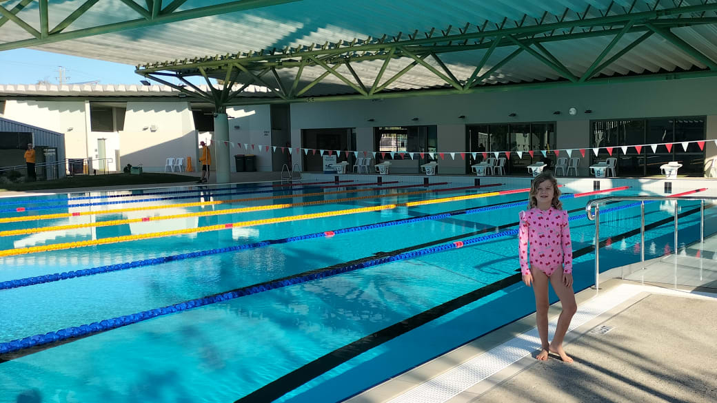 Romy stand in front of the outdoor lane swimming pool at the PCYC Capricorn Coast Aquatic Centre in Cooee Bay near Yeppoon.